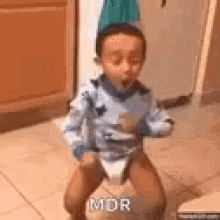 a little boy is sitting on a bouncy ball in a kitchen .