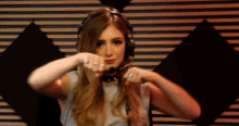 a woman wearing headphones and a microphone holds her fist up