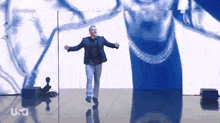 a man in a suit is dancing in front of a screen that says hammer