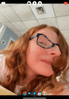 a woman wearing glasses looks at the camera with a red x on the bottom right