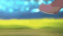 a blurry picture of a person 's foot in a field with a blue sky in the background