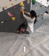a woman is climbing a climbing wall and the number 1 is on the floor