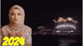 a woman in a hijab is praying in front of a fireworks display that says 2024 on it