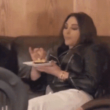 a woman is sitting on a couch holding a plate of food in her hands .