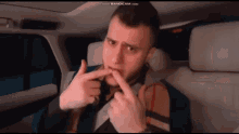 a man in a car is making a funny face with his finger in his mouth