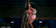 a woman in a pink top and shorts is standing in a dark room with the hashtag pranay_varma