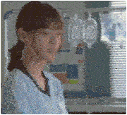 a woman in a blue scrub is standing in a hospital room with iv bags hanging from the wall .