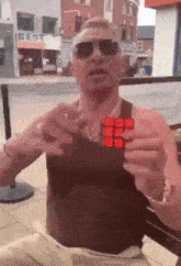 a man is holding a red rubik 's cube in front of a building that says best
