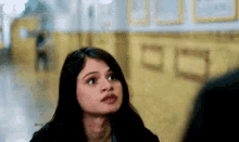 a woman is looking up at something in a hallway while standing next to a man .