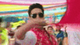 a man wearing sunglasses stands in front of a crowd