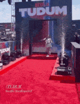 a woman is dancing on a red carpet in front of a sign that says " tudum "