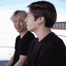 two young men wearing black shirts are sitting next to each other and one of them has a piercing in his ear