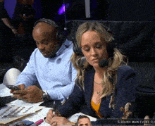 a man and a woman wearing headphones sit at a table in front of a screen that says 5 round main event