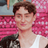 a man with curly hair and a white tank top