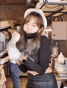a woman wearing a black mask and a white hat is in a kitchen