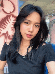 a woman in a black shirt takes a selfie in front of a pink wall