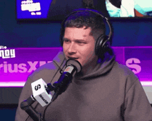 a man wearing headphones is talking into a siriusxm radio station microphone