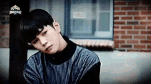a young man is sitting in front of a brick building looking at the camera .