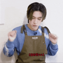 a man wearing a blue sweater and an apron with the word daishii on it
