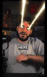 a man with a beard is wearing a shirt that says ' here ' on it