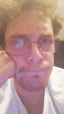 a man wearing glasses and a white shirt is making a face