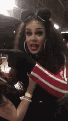 a drag queen is wearing a mickey mouse costume and pointing at something .
