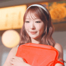 a woman wearing a headband is holding a red bag