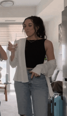 a woman in a black tank top is holding a wine glass