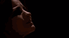 a close up of a woman 's face in a dark room with a hood on .