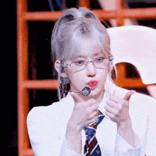 a young woman wearing glasses and a tie is giving a thumbs up .