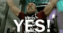 a wrestler with his arms in the air is saying yes !