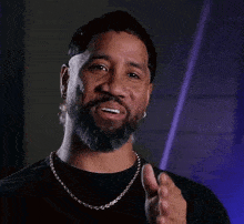 a man with a beard is wearing a gold chain around his neck and smiling .