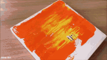 a person is applying orange paint to a canvas with wow art written on the bottom