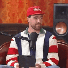 a man wearing a red elwood hat is sitting in front of a microphone