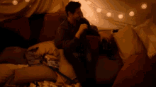 a man is sitting on a couch holding a remote control