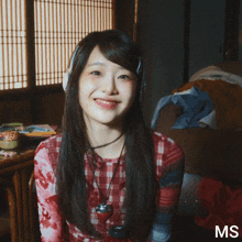 a woman wearing headphones is smiling and the letters ms are on the bottom right
