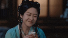 a woman in a blue dress is holding a small white cup