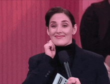 a woman in a black suit is holding a microphone with the letter p on it