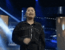a woman wearing glasses and a black shirt is standing on a stage and crying .