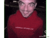 a man wearing a red hoodie with legend never die written on it