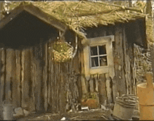 a small wooden house with a window and a basket hanging from it