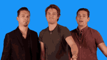 three men are standing next to each other and one has a cross on his shirt