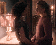 two women holding hands in front of a lamp in a dark room
