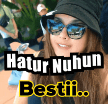 a woman wearing sunglasses and a hat with the words hatur nuhun besti behind her