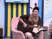 a man sitting in a chair playing a guitar