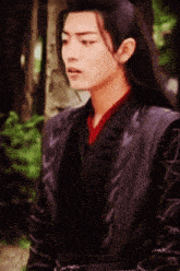 a man with long black hair is wearing a black vest
