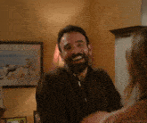 a man with a beard is smiling in a room with a daredevil shots watermark