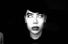 a black and white photo of a man with white eyes in the dark .