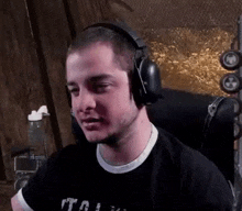 a man wearing headphones is sitting in a chair and making a funny face .