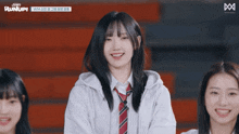 a girl wearing a white hoodie and a red tie is smiling in front of a sign that says runup
